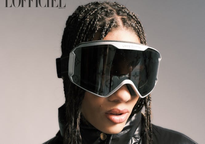 close up shot of model wearing ski goggles and black puffer coat