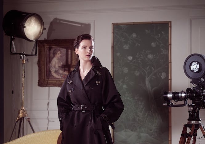 dior pre-fall collection model wearing black trench coat and patent leather boots