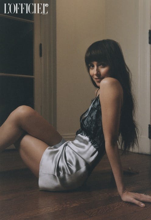Dakota Johnson in a black lace and silver silk dress posing on the floor.