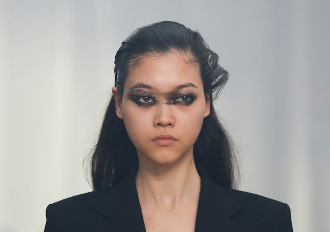 model on runway wearing black blazer with smudged makeup