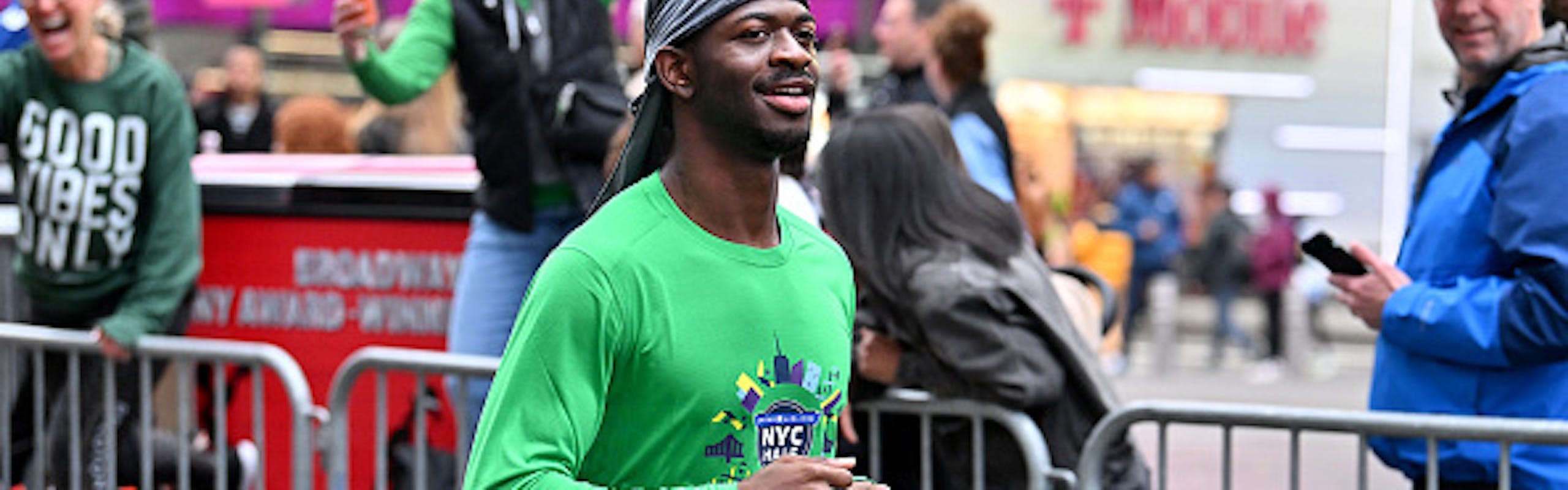 Lil Nas X running the 2024 NYC Half Marathon in a green shirt and black shorts